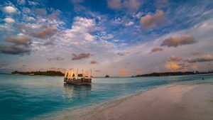 A serene tropical island scene with a floating boat on turquoise waters under a vibrant sunset sky.