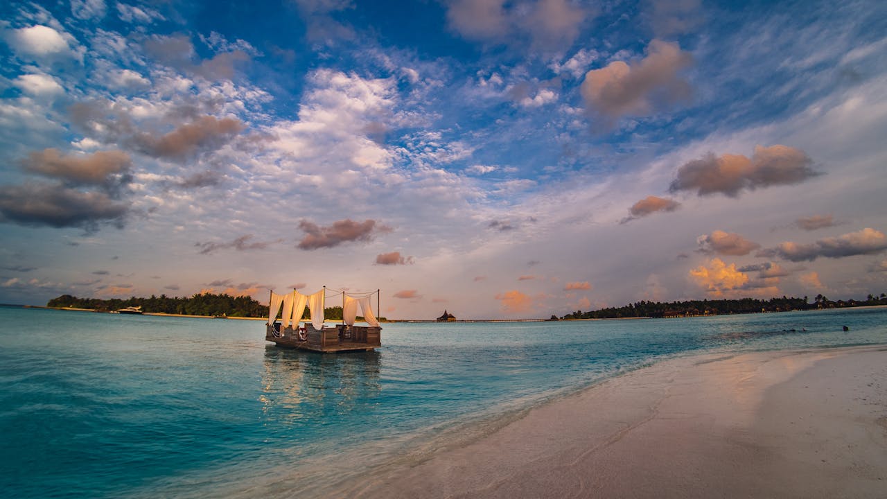 A serene tropical island scene with a floating boat on turquoise waters under a vibrant sunset sky.