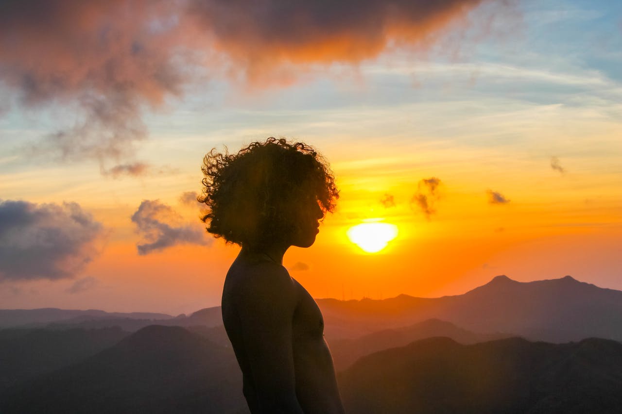 Dramatic sunset with silhouette of a shirtless man on a mountain in Panama, capturing freedom and natural beauty.
