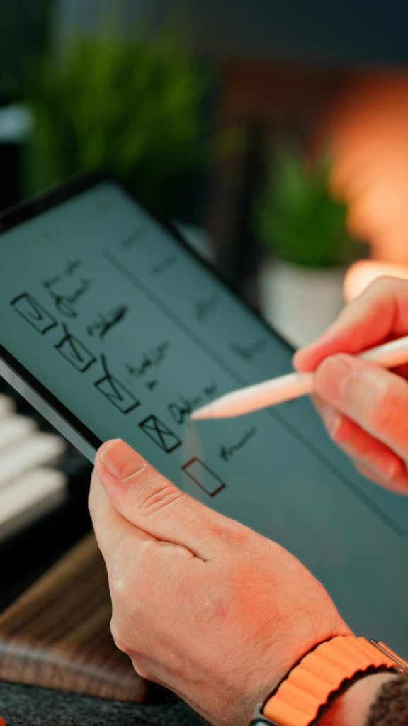 Close-up of hands using a stylus to write on a digital checklist, enhancing productivity.